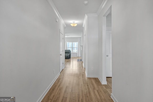 corridor featuring ornamental molding, light wood-type flooring, and baseboards