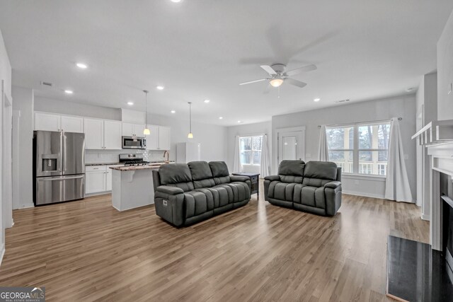 living area with light wood finished floors, a fireplace with flush hearth, plenty of natural light, and recessed lighting