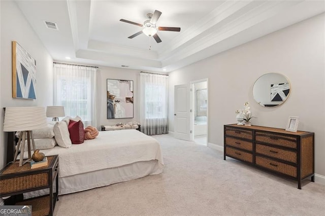 carpeted bedroom with baseboards, visible vents, a raised ceiling, and ensuite bathroom