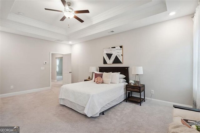 bedroom with light carpet, a ceiling fan, baseboards, a raised ceiling, and crown molding