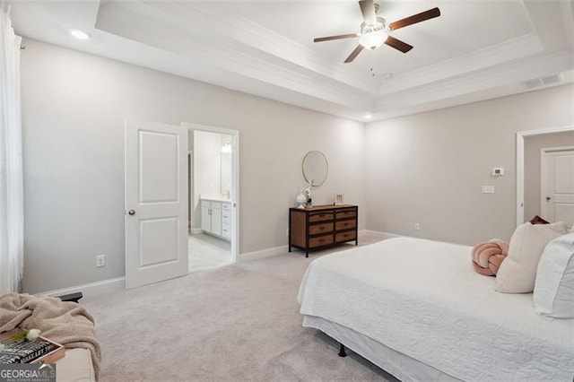 bedroom featuring light carpet, baseboards, a raised ceiling, connected bathroom, and crown molding