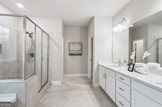 bathroom with a sink, a shower stall, and double vanity