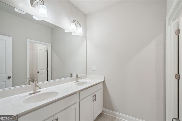 full bathroom with double vanity, tile patterned floors, a sink, and baseboards