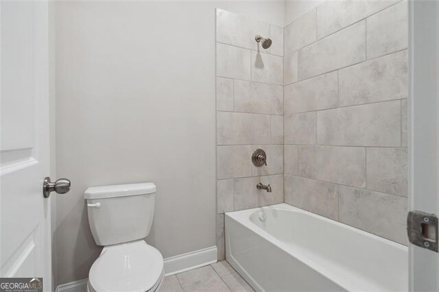 bathroom with bathing tub / shower combination, tile patterned flooring, toilet, and baseboards