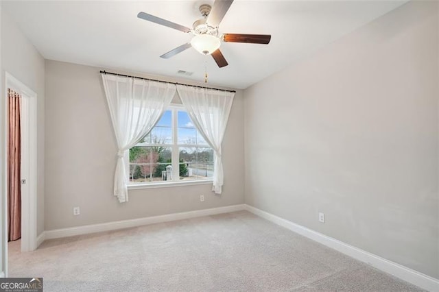 carpeted spare room featuring ceiling fan and baseboards