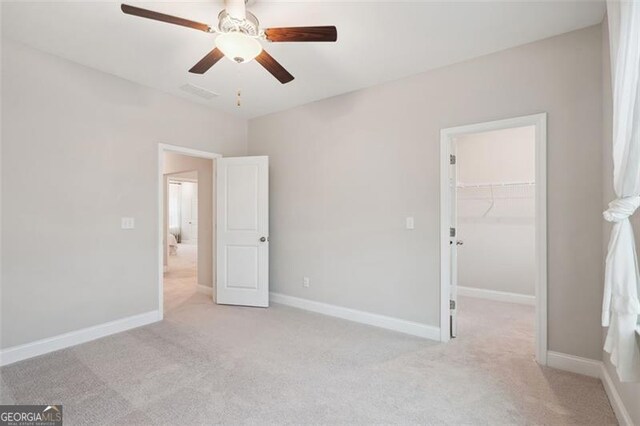 unfurnished bedroom with baseboards, ceiling fan, a walk in closet, carpet floors, and a closet