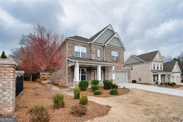 craftsman-style home with covered porch, driveway, and stone siding