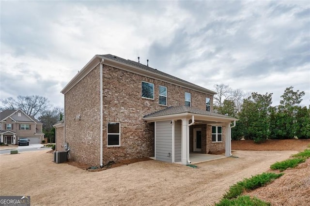 back of property with brick siding, a patio, and central air condition unit