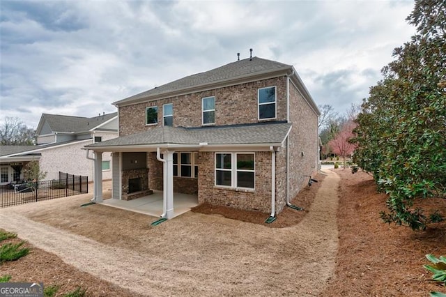 rear view of property with roof with shingles, brick siding, a patio, and fence