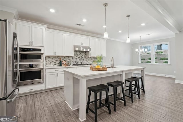 kitchen featuring under cabinet range hood, visible vents, ornamental molding, appliances with stainless steel finishes, and backsplash