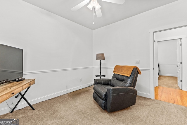 living area featuring ceiling fan, baseboards, and carpet