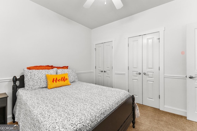 bedroom with ceiling fan, multiple closets, and carpet floors