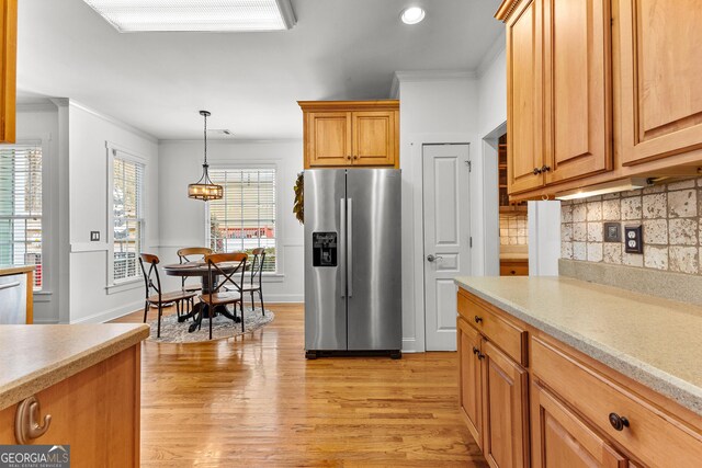 kitchen featuring light wood finished floors, appliances with stainless steel finishes, crown molding, and light countertops