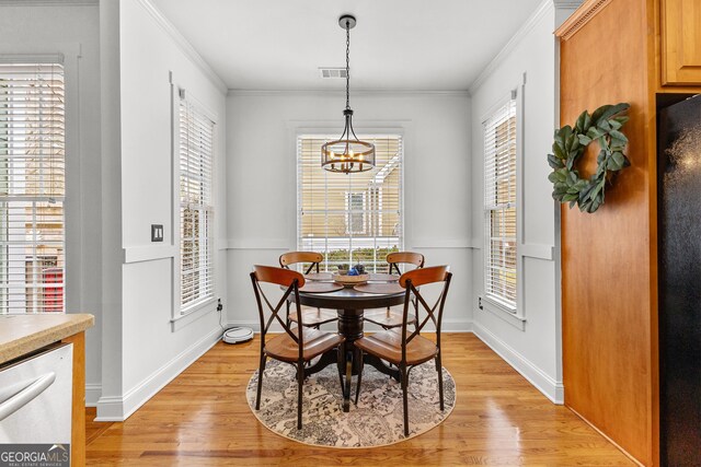 dining area featuring visible vents, baseboards, ornamental molding, light wood-style flooring, and an inviting chandelier