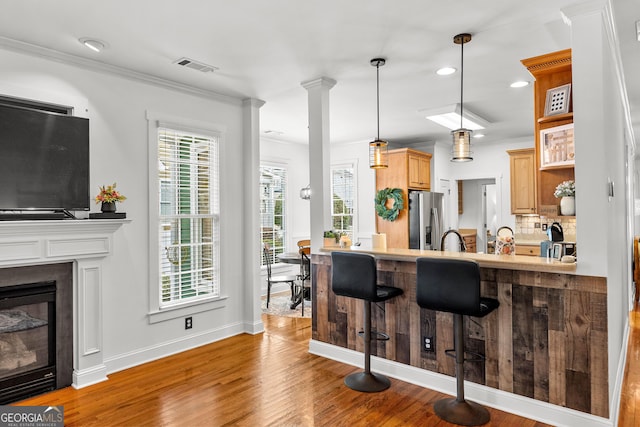 kitchen featuring visible vents, a kitchen breakfast bar, wood finished floors, a peninsula, and stainless steel fridge with ice dispenser