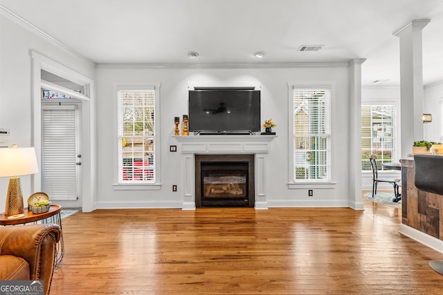 living room with visible vents, plenty of natural light, crown molding, and wood finished floors