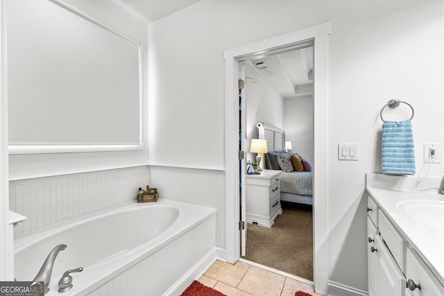 ensuite bathroom with tile patterned floors, a garden tub, ensuite bathroom, wainscoting, and vanity