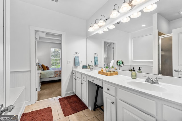 ensuite bathroom featuring a sink, a stall shower, double vanity, and tile patterned flooring