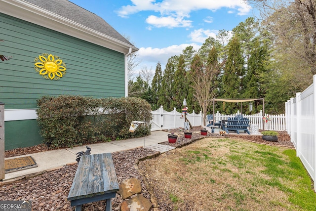 view of yard with a patio, a fenced backyard, and a gate