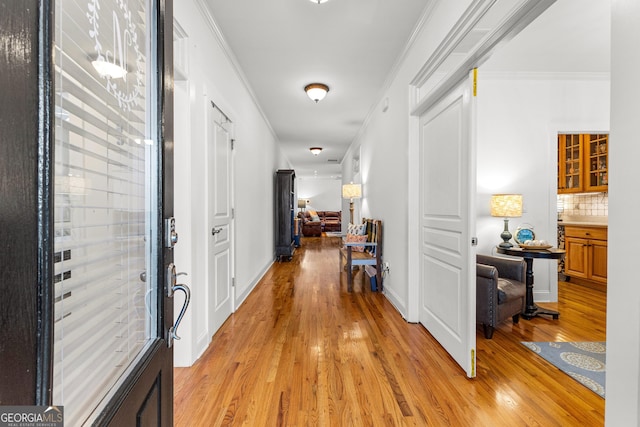 foyer featuring baseboards, light wood-type flooring, and ornamental molding