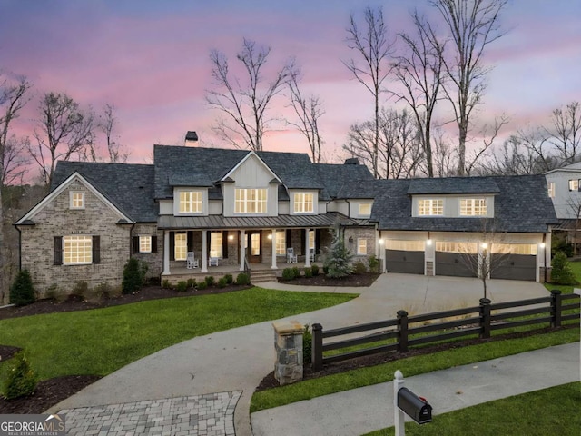 modern farmhouse style home featuring a porch, a fenced front yard, driveway, a standing seam roof, and a chimney