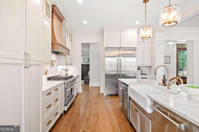 kitchen featuring light stone countertops, premium range hood, glass insert cabinets, and high end appliances