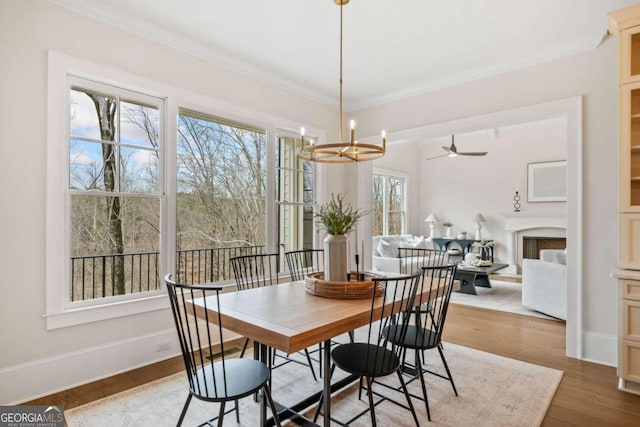 dining room with crown molding, a fireplace, baseboards, and wood finished floors