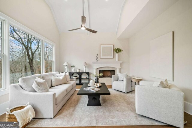 living room with vaulted ceiling, ceiling fan, a fireplace, and wood finished floors