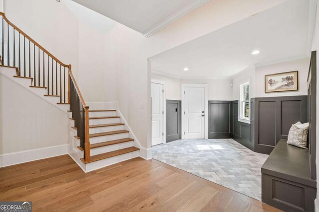 entrance foyer with ornamental molding, recessed lighting, stairway, and wood finished floors