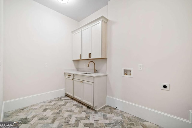 washroom featuring hookup for a washing machine, hookup for an electric dryer, a sink, baseboards, and cabinet space