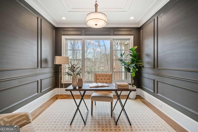 office featuring crown molding, light wood-style floors, and a decorative wall