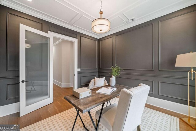 office space featuring light wood finished floors, visible vents, coffered ceiling, crown molding, and a decorative wall