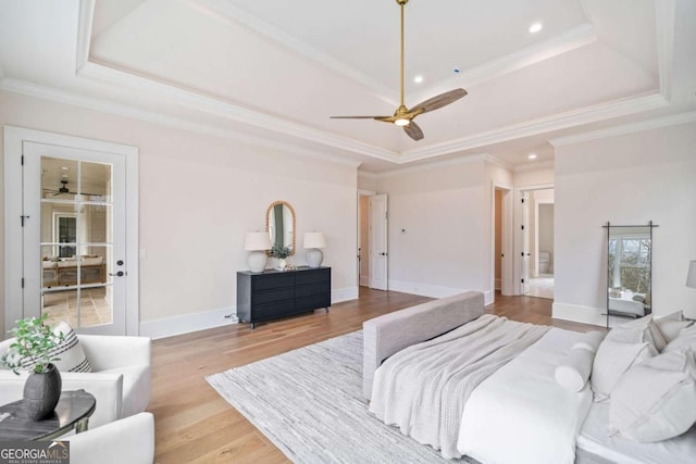 bedroom with a tray ceiling, crown molding, recessed lighting, light wood-type flooring, and baseboards