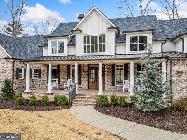 modern farmhouse with covered porch, brick siding, a standing seam roof, and a chimney