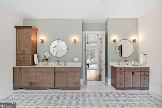 full bathroom featuring two vanities, a sink, and baseboards