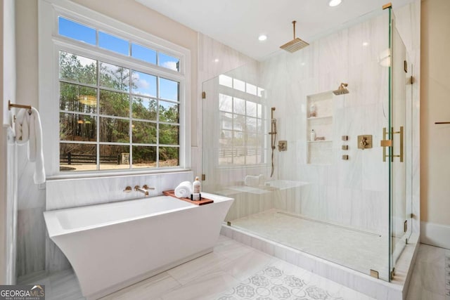 full bath featuring recessed lighting, a soaking tub, a shower stall, and tile walls