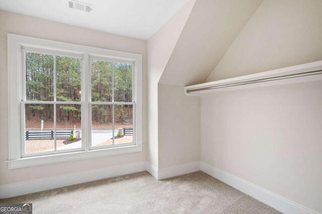 spacious closet featuring vaulted ceiling, visible vents, and light colored carpet