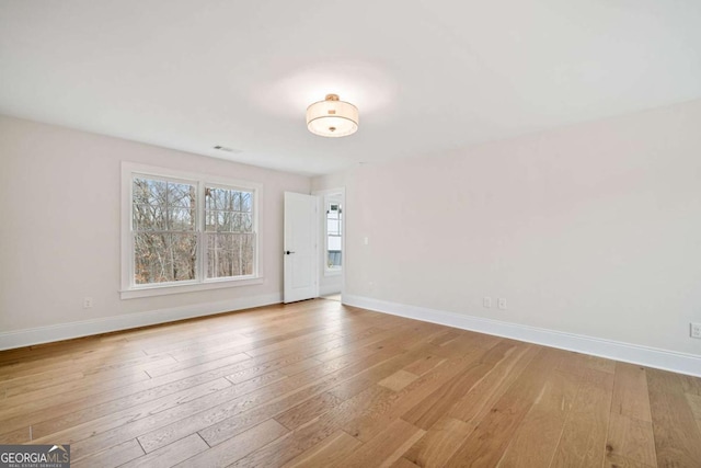 spare room featuring light wood-style floors, visible vents, and baseboards