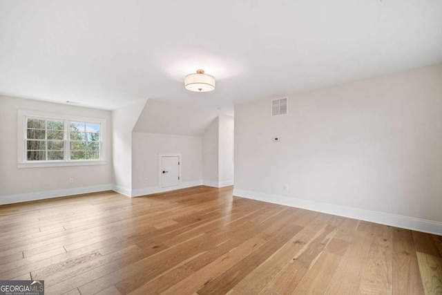 additional living space with light wood finished floors, visible vents, and baseboards