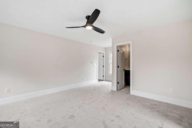 unfurnished bedroom with baseboards, ensuite bathroom, a ceiling fan, and light colored carpet