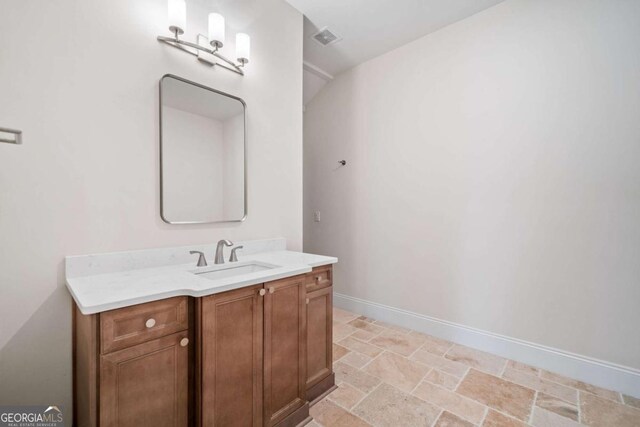 bathroom featuring baseboards, vanity, visible vents, and stone tile floors