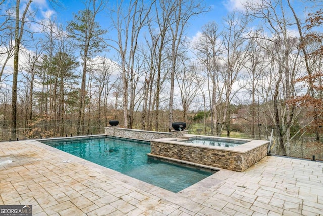 pool with an in ground hot tub and a patio area