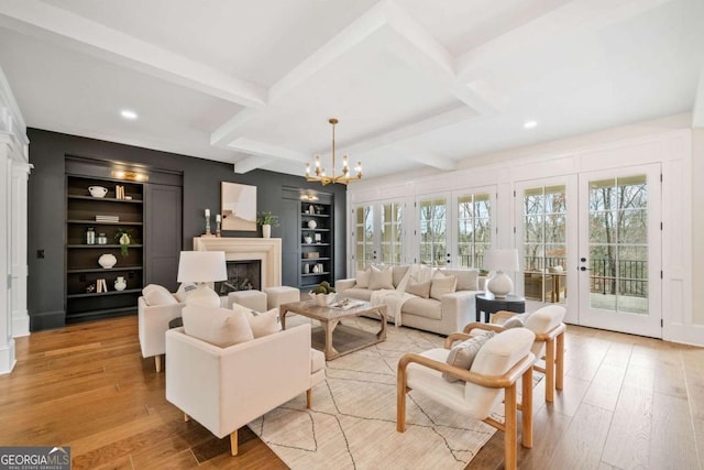 living room featuring light wood-style flooring, built in features, beam ceiling, and french doors