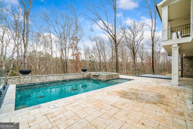 outdoor pool with a patio area and an in ground hot tub