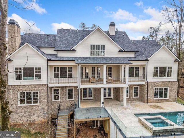 rear view of property with a balcony, a chimney, stairs, french doors, and a patio area