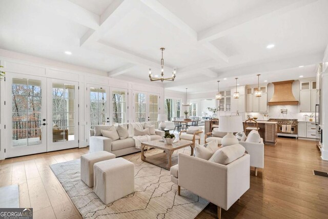 living area with light wood finished floors, coffered ceiling, french doors, a chandelier, and beam ceiling