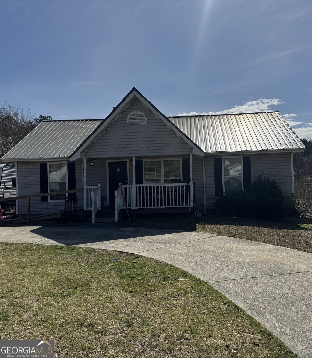 single story home featuring a porch, a front yard, and metal roof