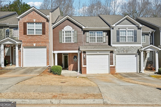 townhome / multi-family property with a garage, driveway, brick siding, and a shingled roof