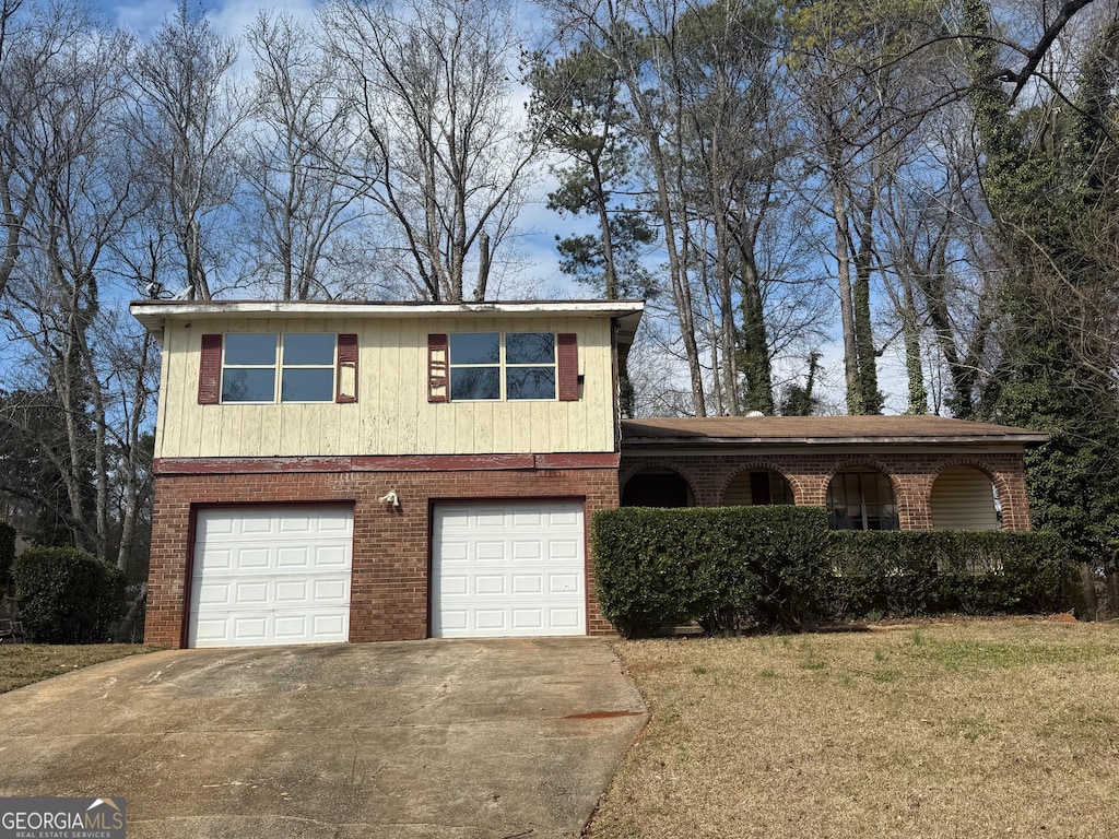 view of front of home featuring a garage, a front yard, brick siding, and driveway