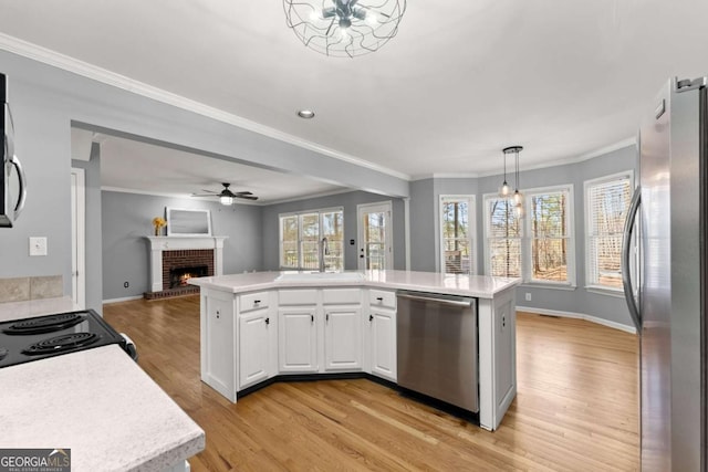 kitchen with white cabinets, appliances with stainless steel finishes, open floor plan, light countertops, and a sink